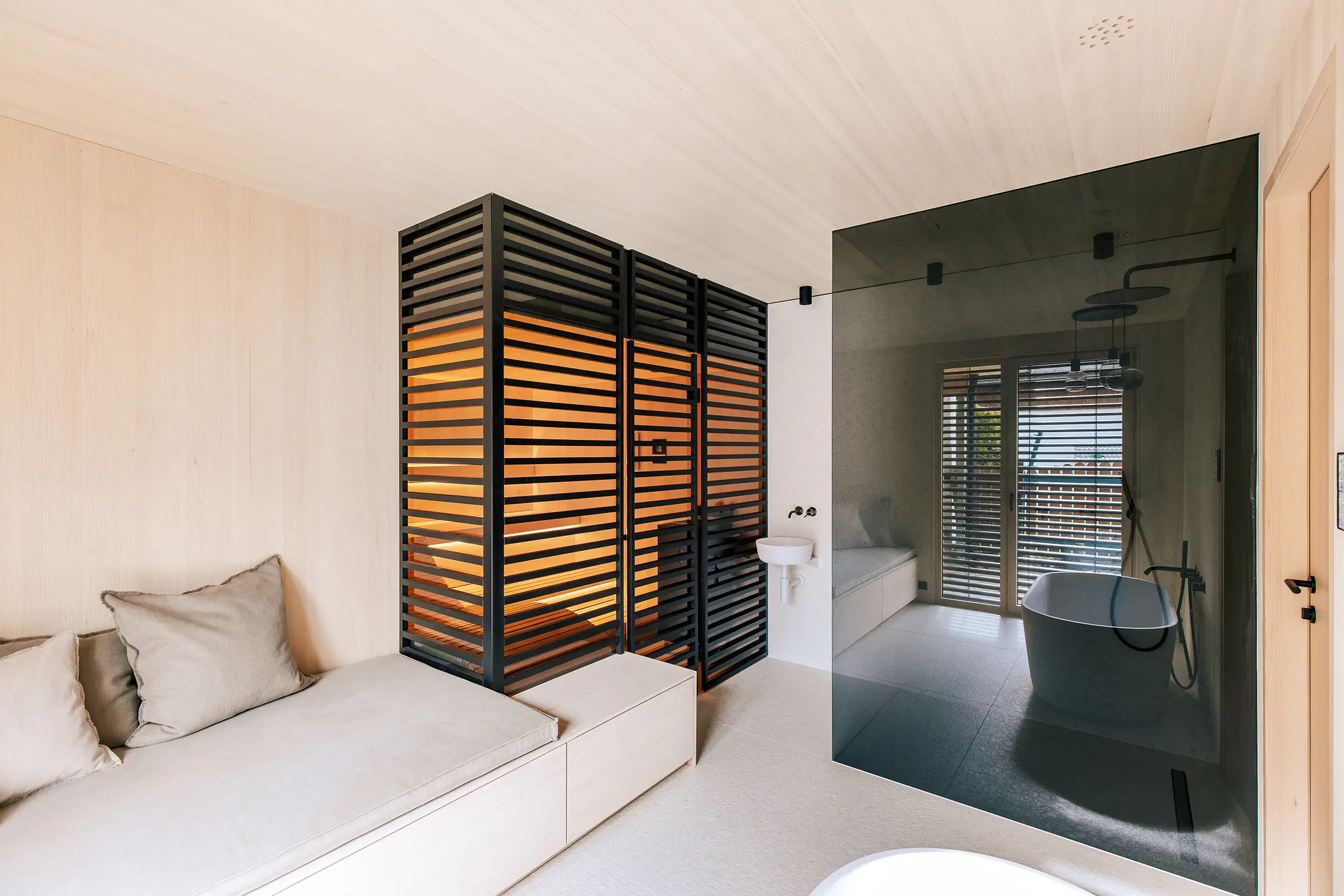 Sauna in individuellem Design mit schwarzem Holzstreben-Sichtschutz, Daybed und Dusche in einem modernen Badezimmer