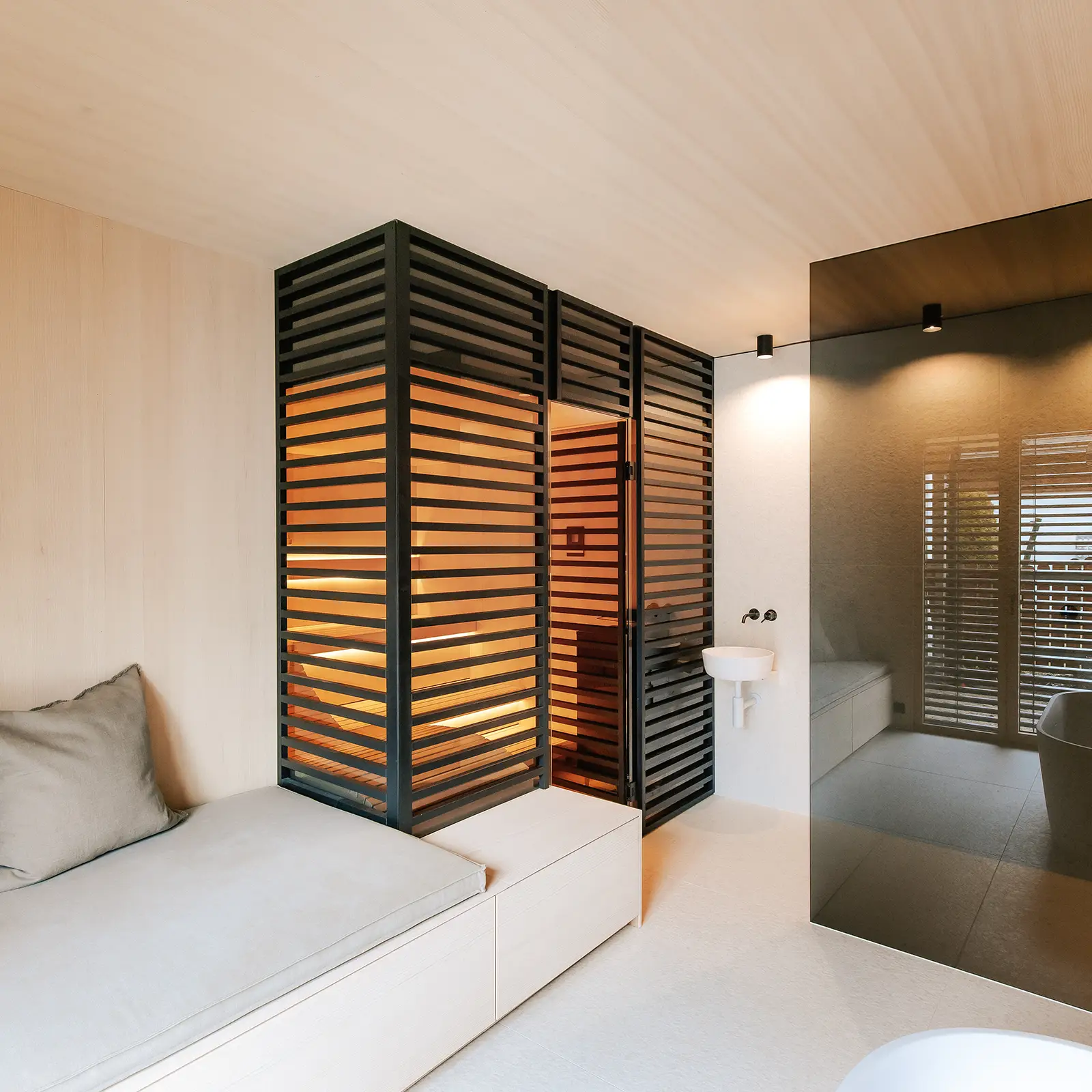 Verglaste Sauna im Japandi Stil mit schwarzen Holzstreben als Sichtschutz und Daybed im modernen Badezimmer