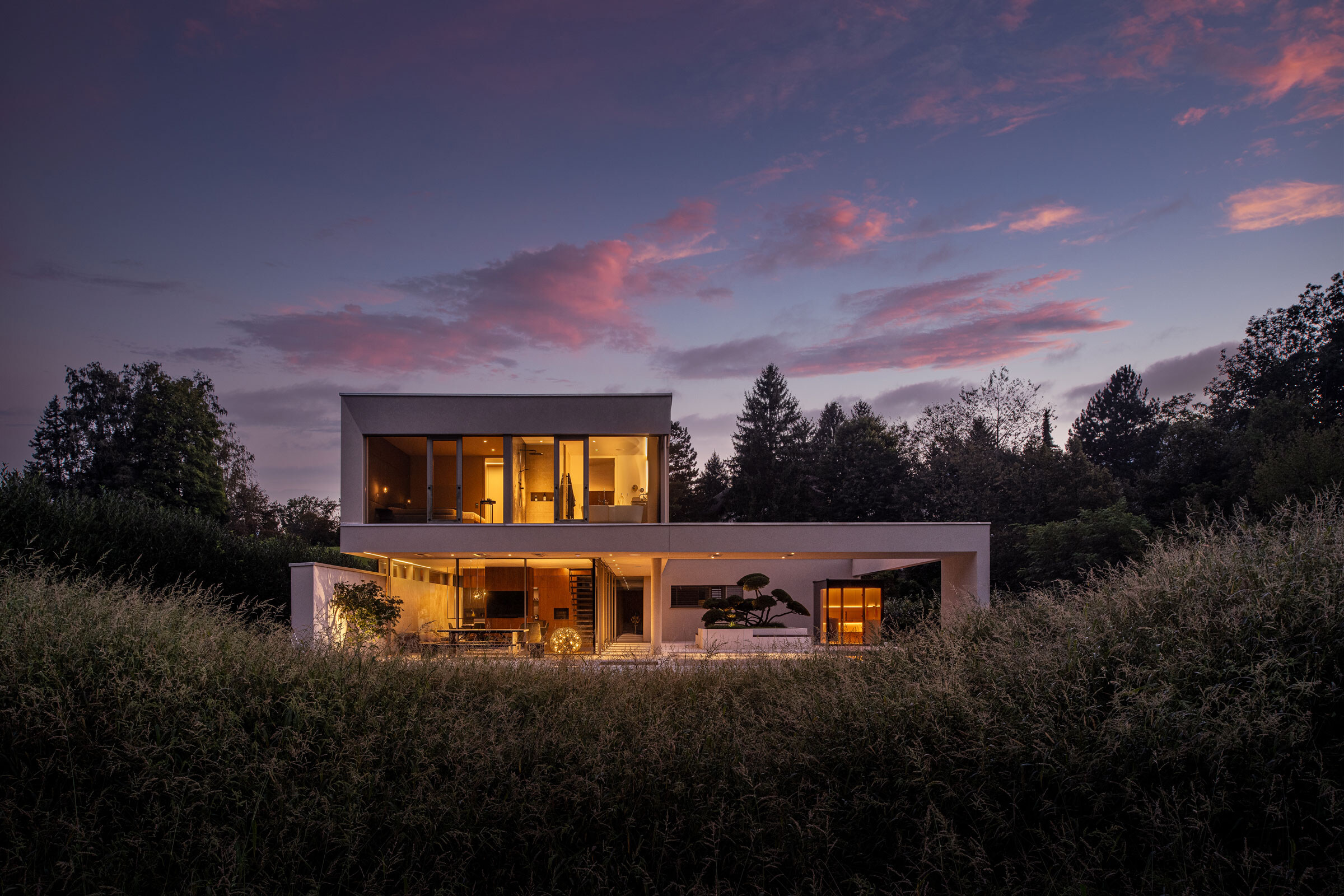 Modernes Architektenhaus mit Design Sauna auf einer Terrasse in der Abenddämmerung