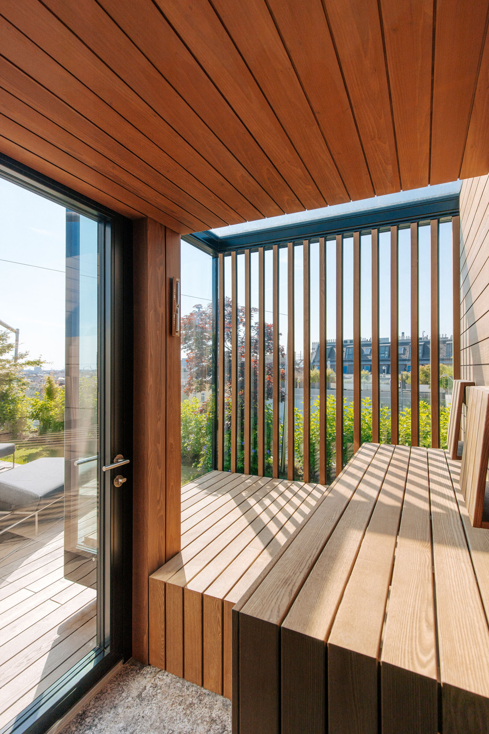 Sauna in modernem Design aus Akazienholz mit Dachverglasung, Windowseat, seitlichem Sichtschutz und Zugang zur Terrasse