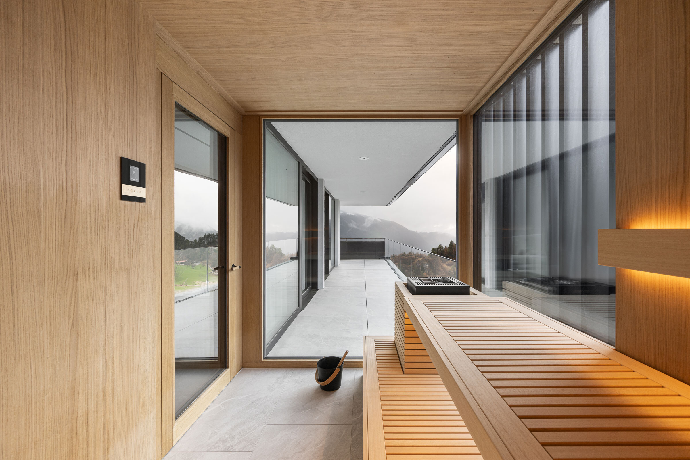 Individuelle Luxus-Sauna von Deisl im Japandi-Stil mit schwarzem Sichtschutz, Glasfront und Ausblick auf einen Balkon