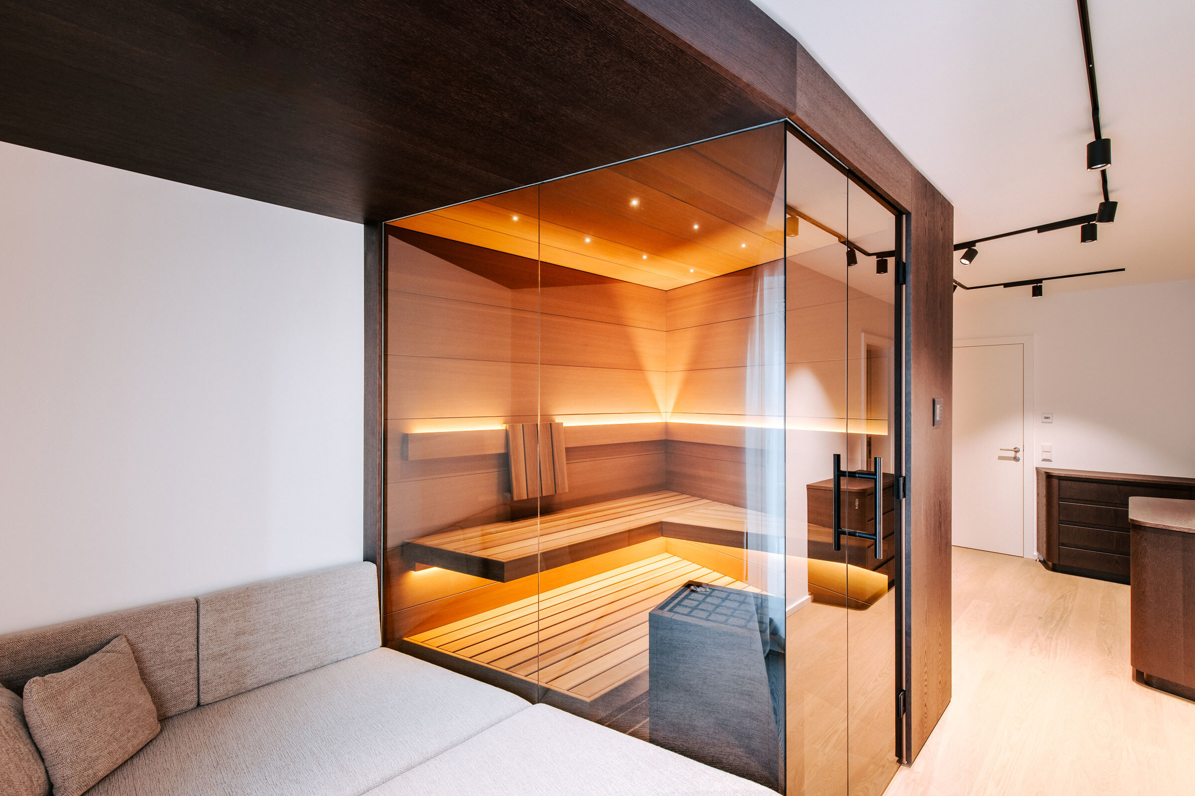 Kleine Sauna nach Maß mit Daybed und dunkler Holzverkleidung in einem modernen Ankleidezimmer