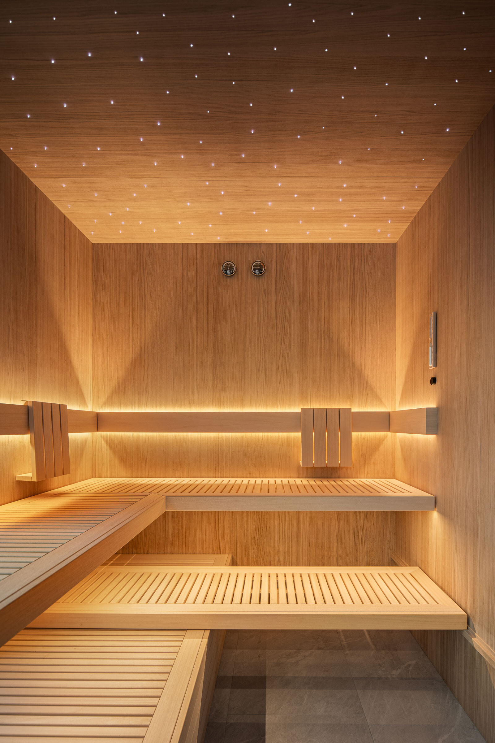 Dezent beleuchtete Luxus-Sauna Interior aus hellem Eichenholz mit in die Decke integriertem Sternenhimmel