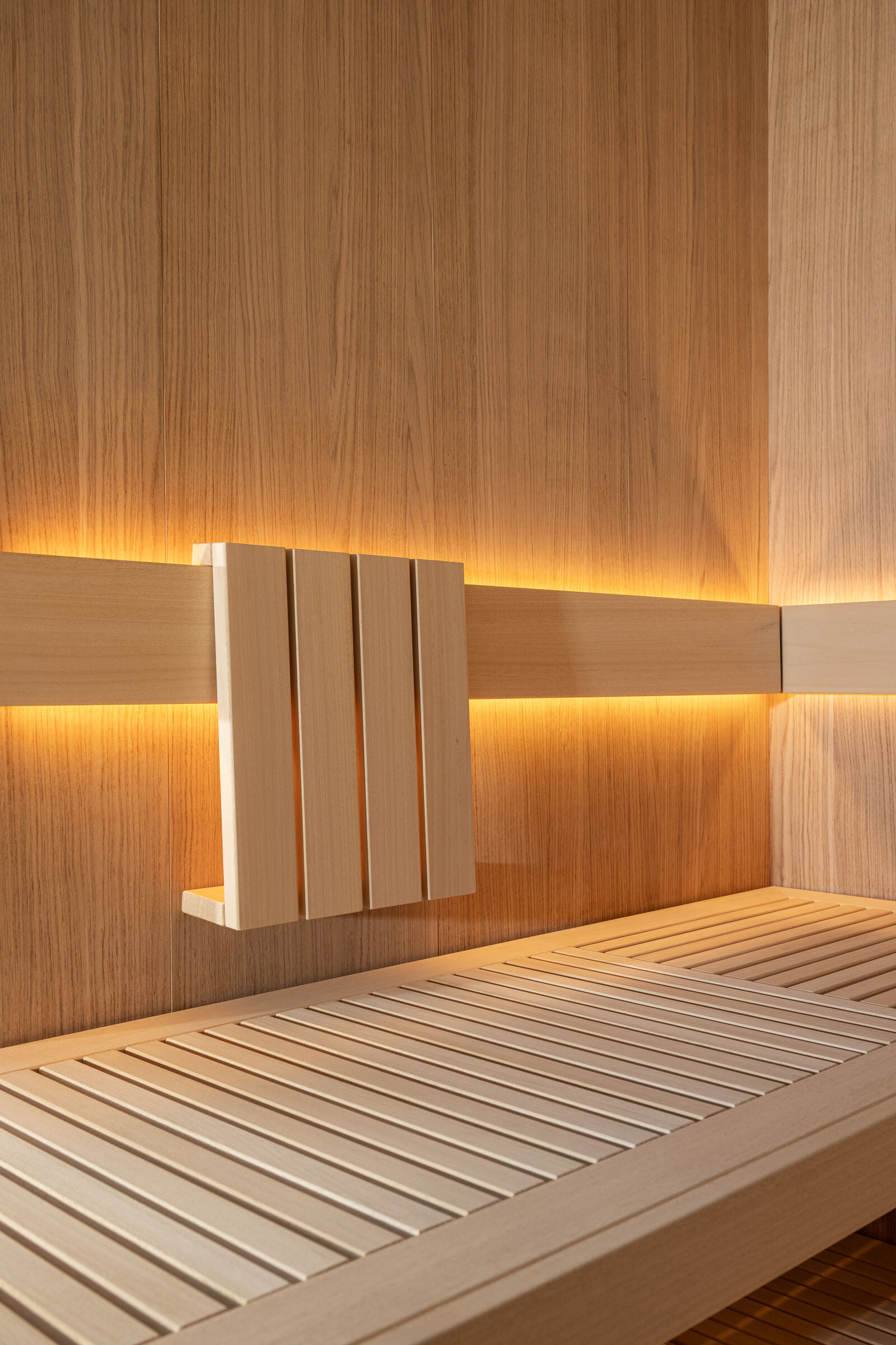 Minimalistisches Sauna Interior im Scandi-Stil aus hellem eichenholz und mit Rückenlehne und dezenter Beleuchtung