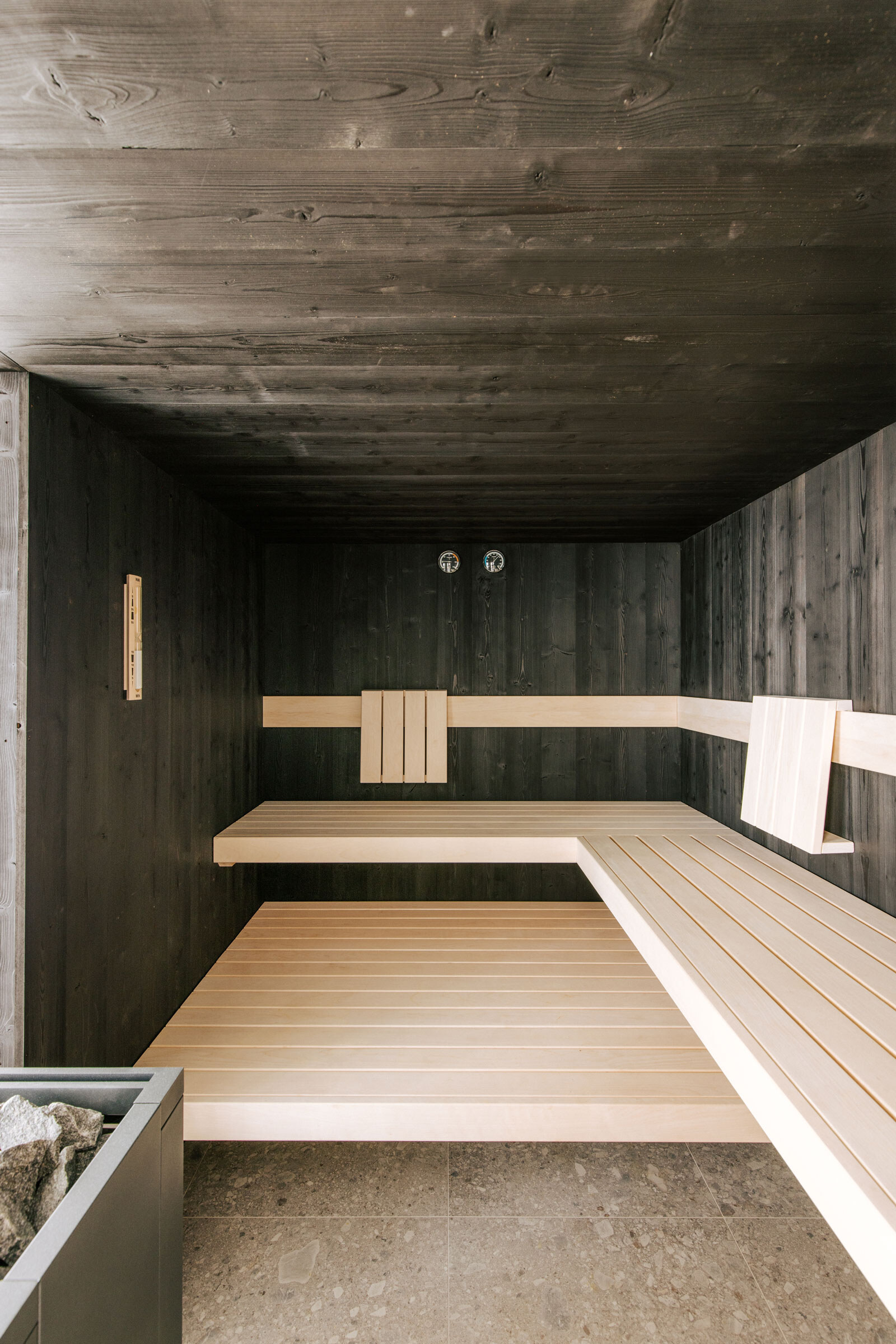 Minimalistisches Sauna-Interior in schwarzer Thermofichte mit Saunabänken aus hellem Espenholz