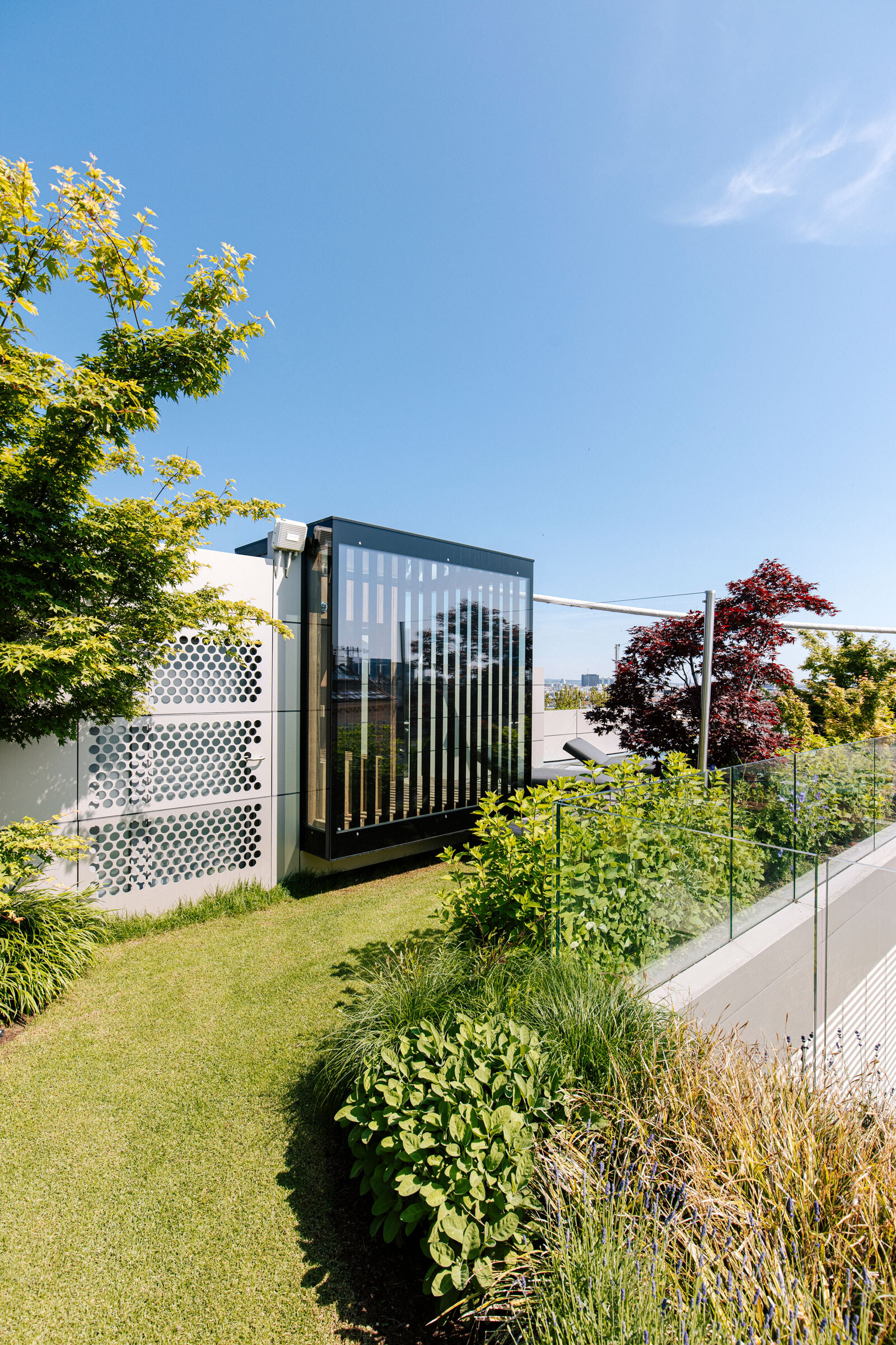 Moderne Outdoor-Sauna im Dachgarten mit Verglasung und Sichtschutz aus Holzlamellen