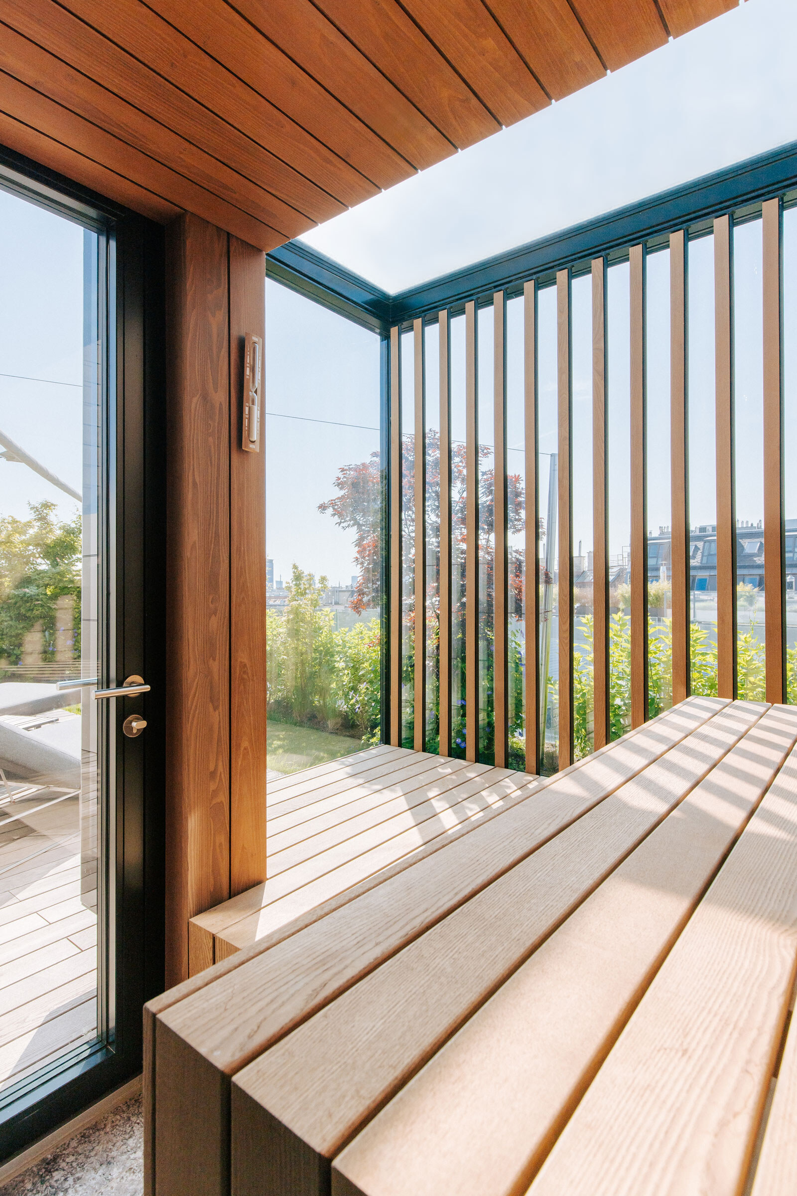 Maßgeschneiderte Sauna mit Panorama- und Dachverglasung, Windowseat und seitlichem Sichtschutz aus Holzstreben