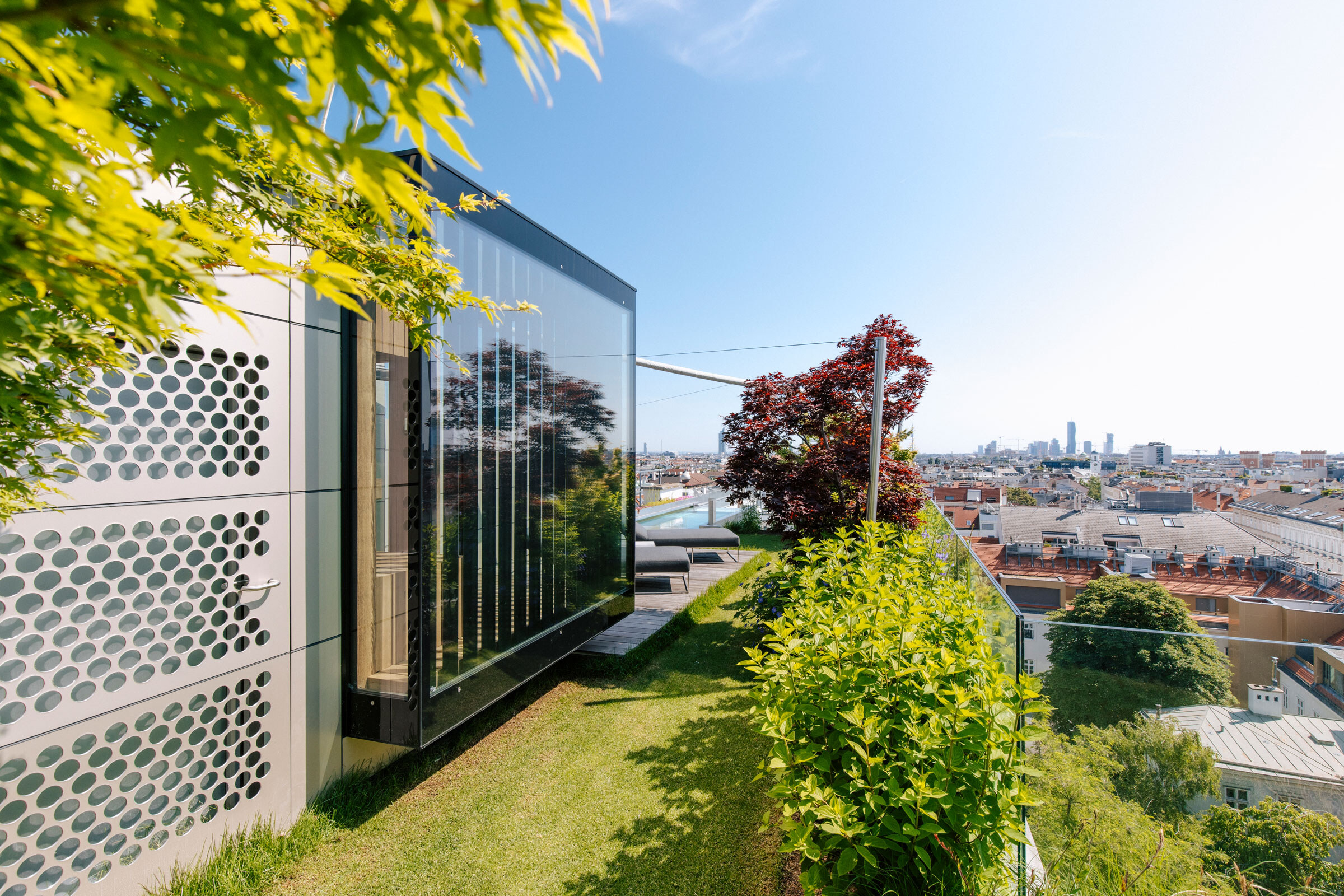 Schwarz verglaste Aussensauna mit Sichtschutz-Lamellen in einem Dachgarten mit Ausblick über Wien